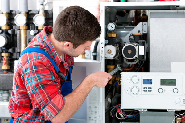 Heating technician repairing boiler controls in San Clemente