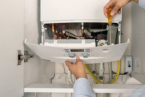 Heating technician repairing a residential boiler in San Clemente