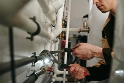Technician inspecting commercial plumbing pipes in San Clemente
