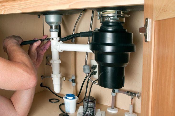 Plumber repairing a garbage disposal in San Clemente