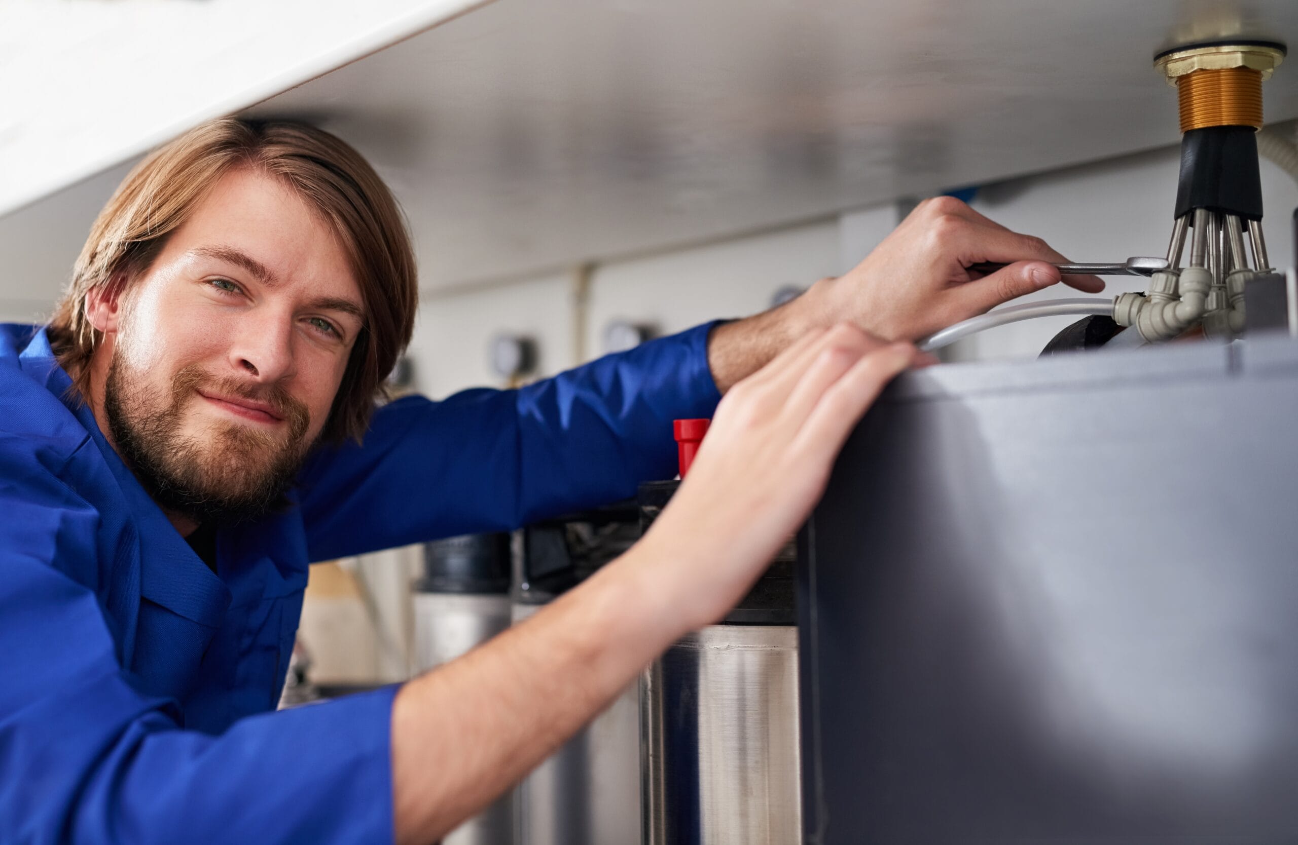 Technician servicing a residential water heater tank in San Clemente